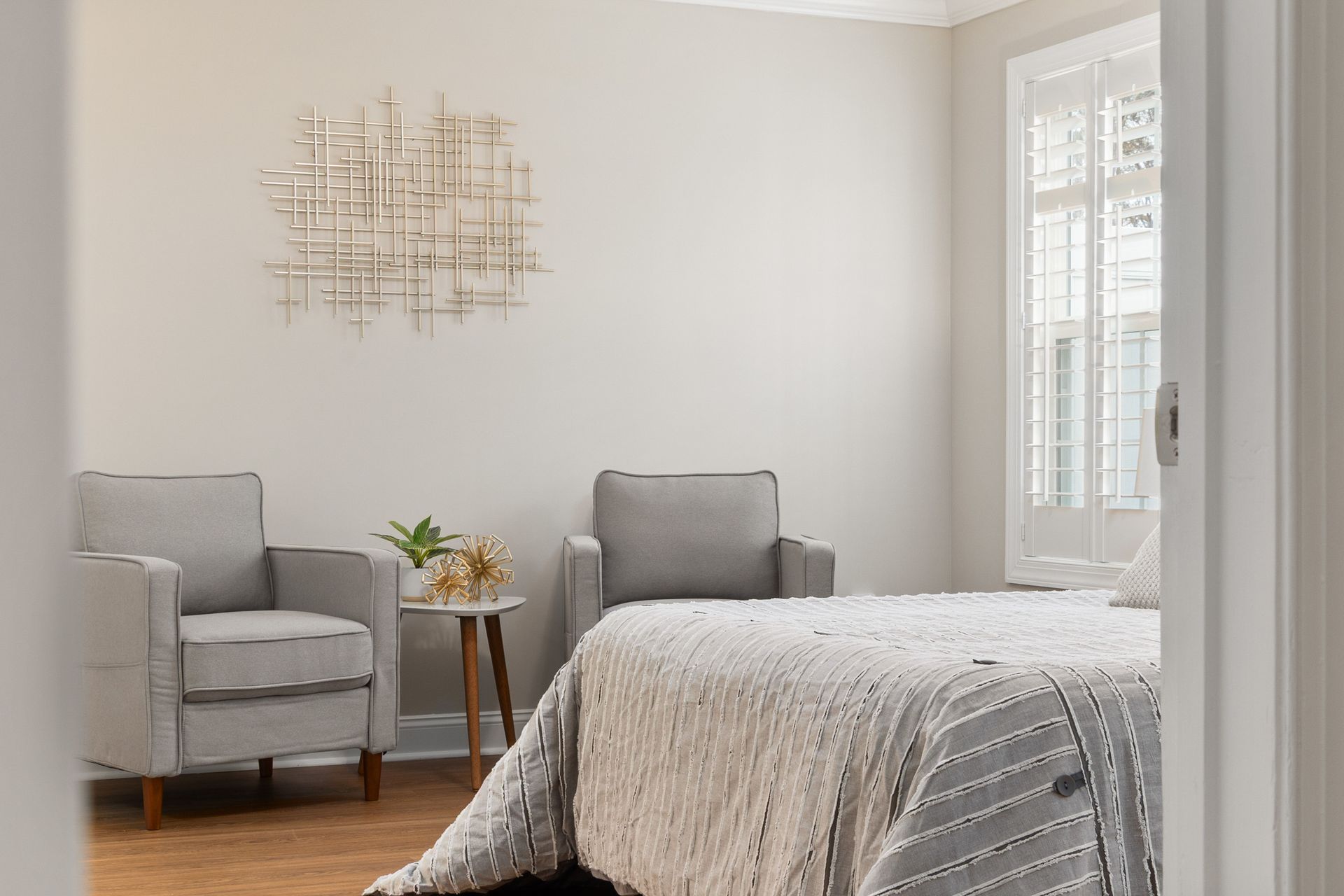 A bright, modern bedroom with grey armchairs and a stylish bed. Perfect for design inspiration.