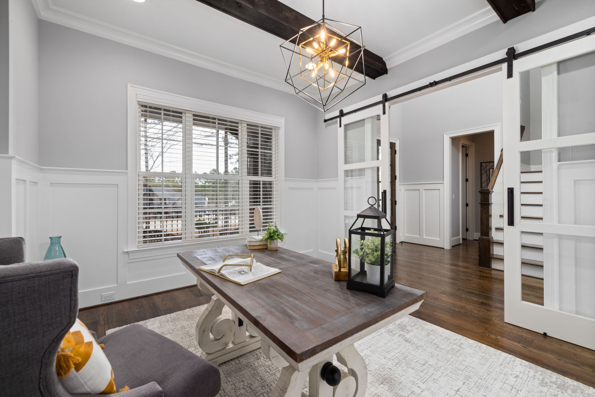 Bright living room with modern decor, featuring a wooden table, lantern, and sliding barn doors.