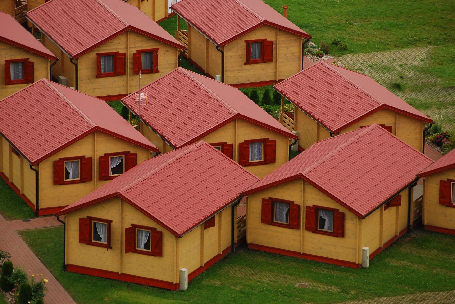 Aerial perspective of a cluster of wooden houses with striking red roofs in a rural setting.